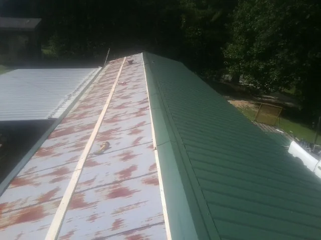 Old rusted panels beside newly installed green metal roofing — Wind Damage Roof Repair by Roofing Brothers in Green Valley Lake