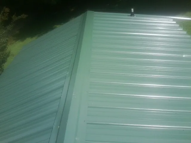 New green metal panels meeting at the ridge of a roof — Flat Roof Repair work by our crew in Green Valley Lake