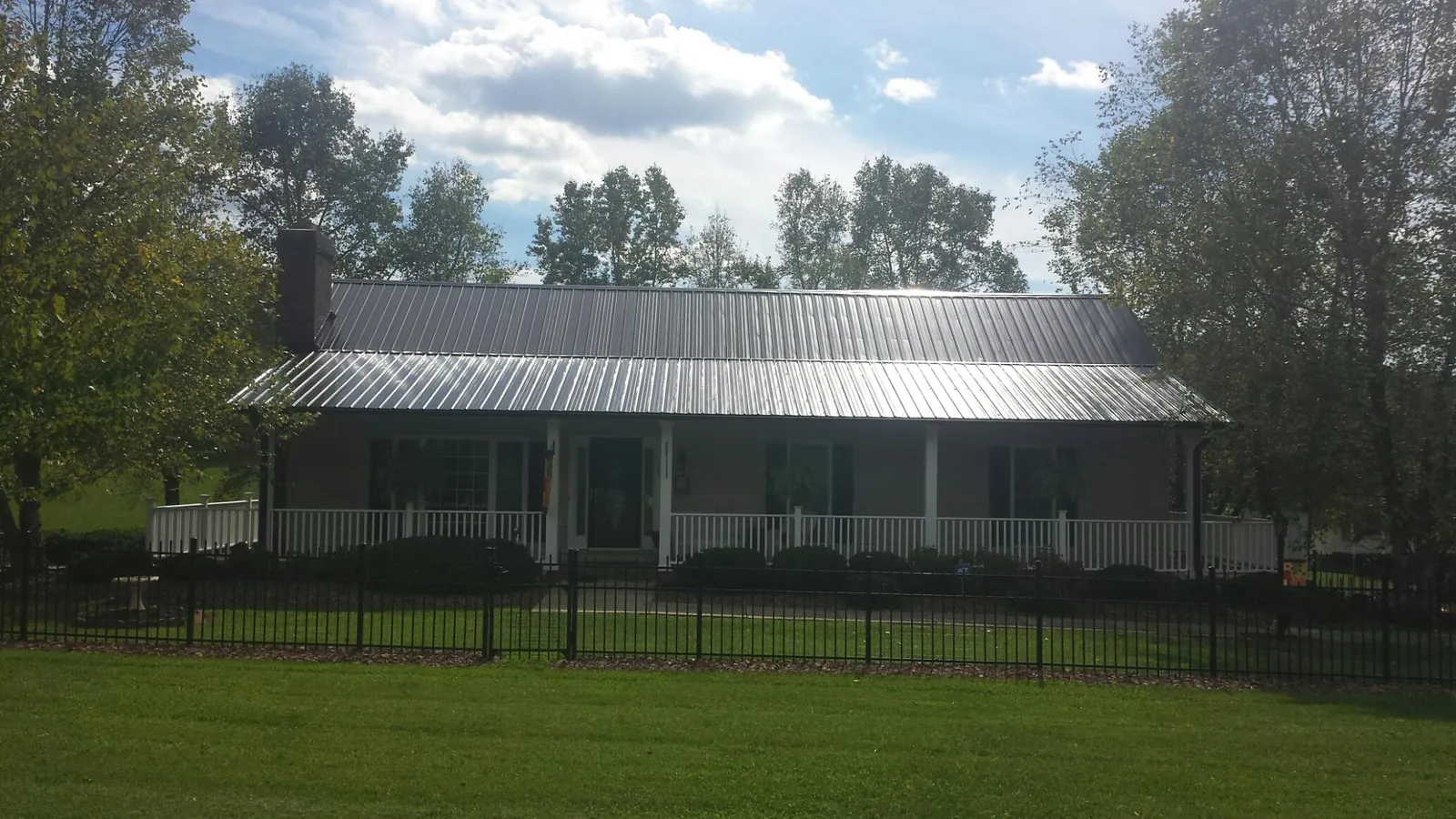 Gray metal roof on a brick ranch with a full width front porch — Gutter Guard Installation work by our crew in Green Valley Lake