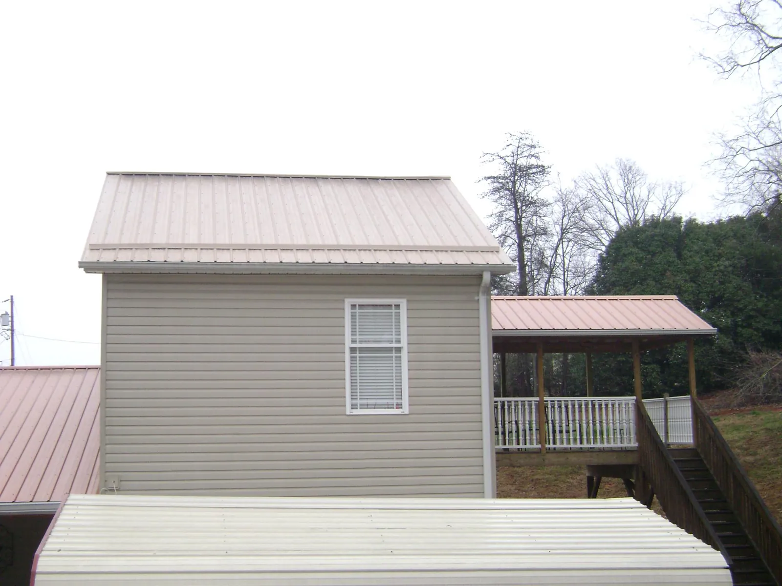 Tan metal roofs on a two story addition and attached porch, from a Roof Replacement job in Green Valley Lake