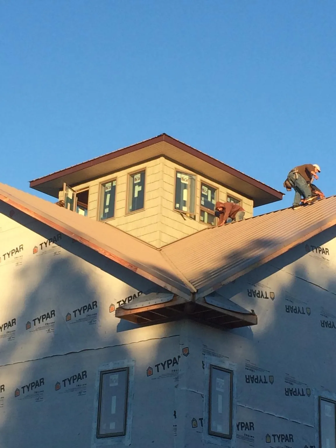 Roofers working around a rooftop cupola on a new metal roof at sunset — Roof Waterproofing in Green Valley Lake by Roofing Brothers